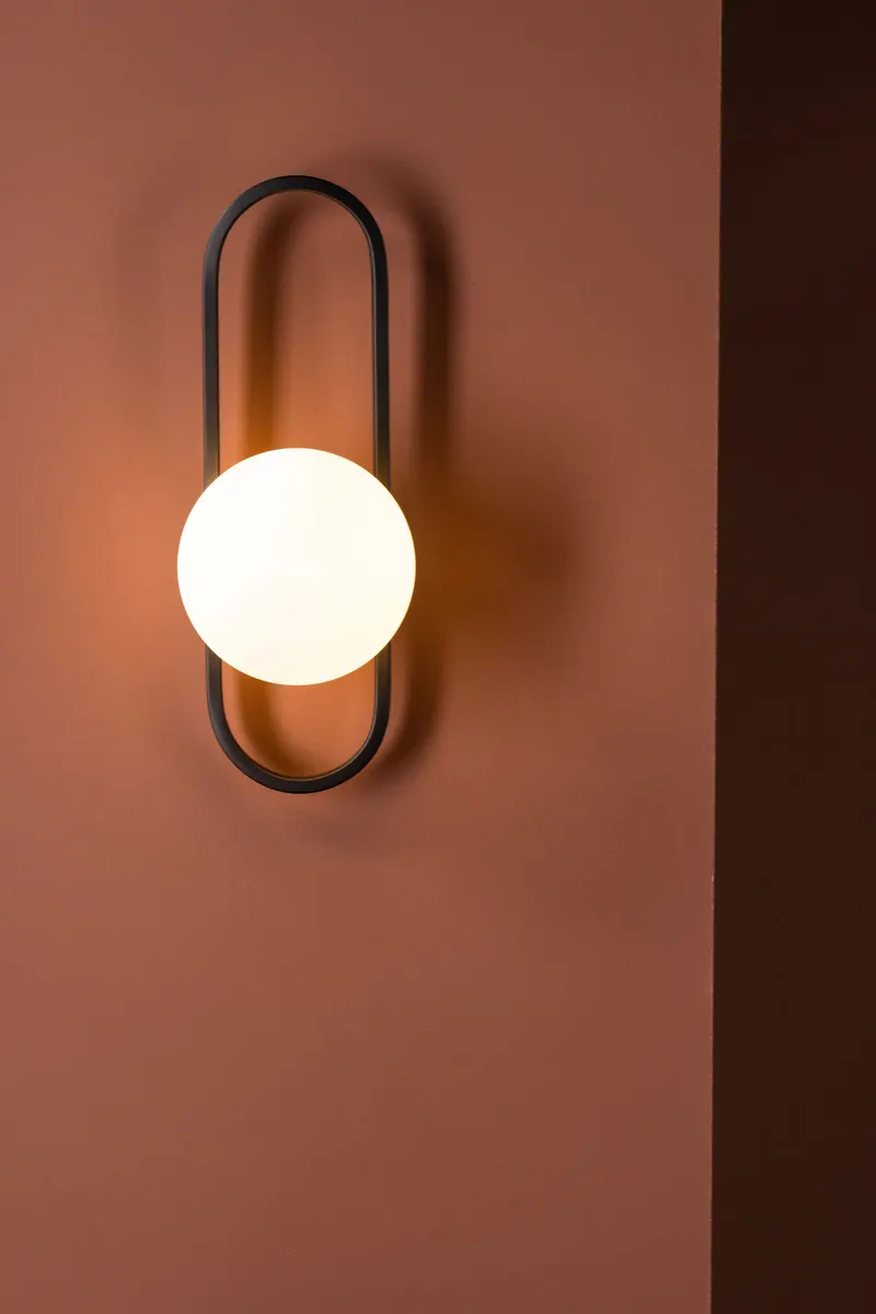 Alpes Wandleuchte mit ovalem Eisenbügel und Glaskugel, im Wohnraum, Ansicht 2